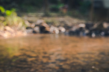 blurred of weir made with stone near the river with reflection in foreground