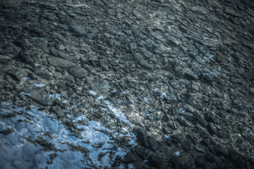 stone under river with reflection, in soft dramatic horror tone