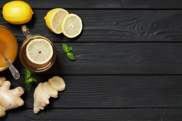 Traditional medicine. Hot tea with lemon and ginger, Honey and Mint on a black wooden background. Place for text. Top view.