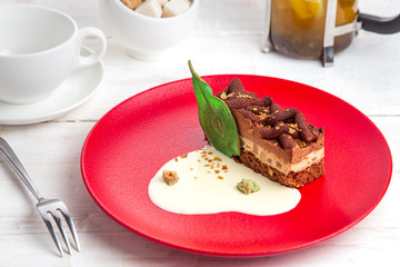 tea time with cake pear baileys. Dessert on a red plate. Background white wooden board, decorated with a teapot with tea, a cup of tea and a sugar bowl