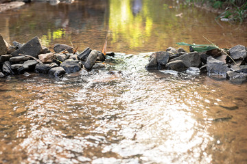 weir in river made from natural stone with people reflection on top