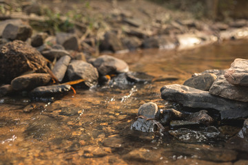 close up of stone that use to make weir in river with water steam flowing