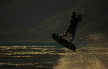 Professional kiter makes the difficult trick on a beautiful background of spray and colourful sunset. Gokova Gulf/Akyaka - Marmaris Mugla. Aegean and Mediterranean sea side of Turkey.