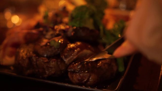 SLOWMO - Cutting a steak on a plate with mushrooms, bacon, broccoli, salad, french fries and gravy at a luxury restaurant - CLOSE UP