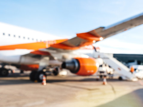 Defocused view of modern aircraft at the international airport tarmac waiting for passengers on a bright sunny day