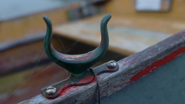 Tight closeup of rusty old oarlock on a wooden rowboat. Cobwebs.