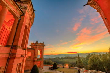 Landscape of hills above Bologna from a window on the portico of San Luca Sanctuary with a scenic sunset light. Side view of arcades of the portico. Aerial view on the church courtyard.