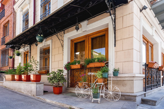 Fototapeta Old narrow street in Tbilisi, Georgia. Old fashioned building with flower pots and decorative bicycle.