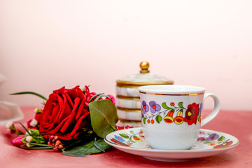 small bouquet of burgundy roses and carnations, a cup of coffee and a sugar bowl on a pink background, morning sketch, boutonniere