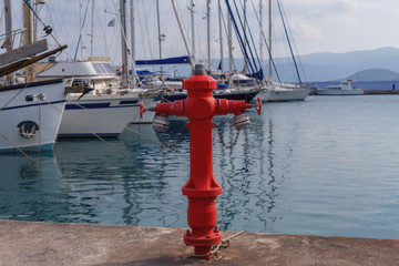 powerful modern fire hydrant on a background of blue sea and snow-white yachts