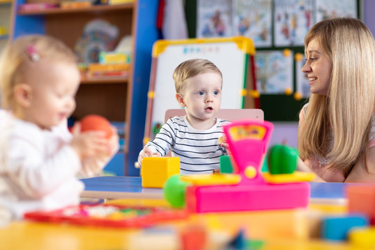 Nursery children play with teacher in kindergarten