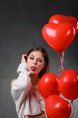 Beautiful young woman with bunch of red heart balloons