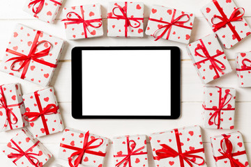 Online shopping holiday background. Tablet screen with copy space on wood with gift box and heart top view. Advertising mockup. Valentine day internet sales concept