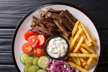 Tasty shawarma bowl with lamb, french fries, vegetables and sauce close-up. horizontal top view