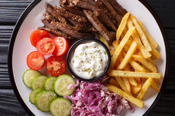 Beef shawarma with vegetables and sauce serving on a plate close-up. Horizontal top view