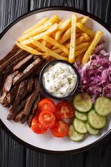 Beef shawarma with vegetables and sauce serving on a plate close-up. Vertical top view