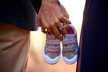 Couple holding hands and child's shoes
