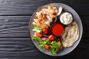 Mediterranean Chicken Shawarma Bowl with hummus, vegetables salad and sauce close-up. Horizontal...