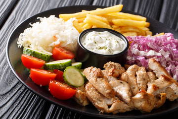 Freshly cooked shawarma plate with chicken, french fries, vegetables and sauce close-up. horizontal