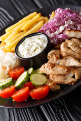 Delicious chicken shawarma with vegetables and sauce on a plate close-up on the table. vertical
