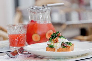 Eggs benedict with brioche, bacon and spinach.