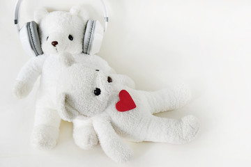 White teddy bear wearing headphones and sleeping on the lap. The day of love and the day of music.