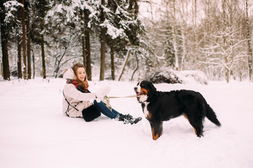 Woman playing with a dog in winter park .Cute girl in a winter park.