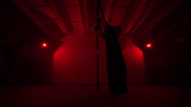 Adult sexy woman dancing dance in an intimate setting. Silhouette of a sexy woman dancing on red background. Pole dance from an old woman