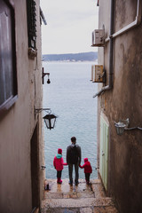 Colorful Old Town street perspective view in Rovinj, Istria, Croatia. Family, father and two daughter looks to the sea from the street
