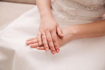 beautiful hands of a young girl with french manicure lie on a white dress
