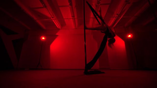 Adult sexy woman dancing dance in an intimate setting. Silhouette of a sexy woman dancing on red background. Pole dance from an old woman
