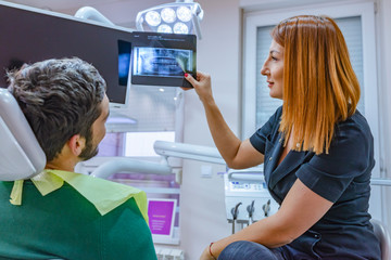 Dentist looking at X-ray image of young man's teeth