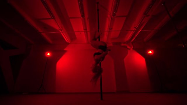 Adult sexy woman dancing dance in an intimate setting. Silhouette of a sexy woman dancing on red background. Pole dance from an old woman