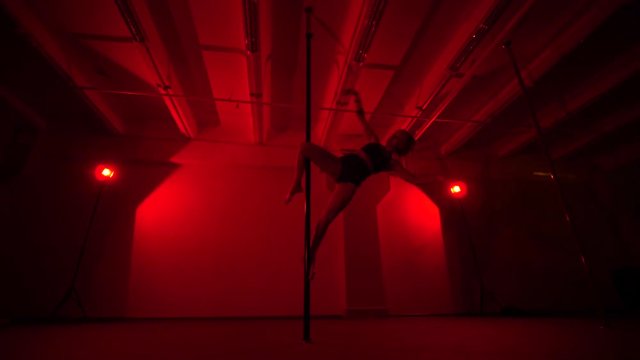 Adult sexy woman dancing dance in an intimate setting. Silhouette of a sexy woman dancing on red background. Pole dance from an old woman