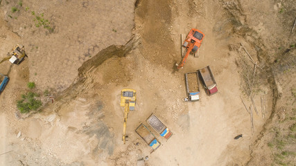 excavator at construction site cuts hill and loads truck with earth. aerial view Heavy machinery prepares the countryside for construction. Excavators are been used in large and small scale