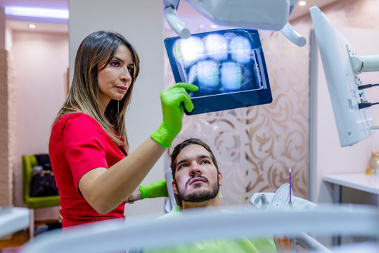 Dentist explaining the details of a x-ray picture to her patient