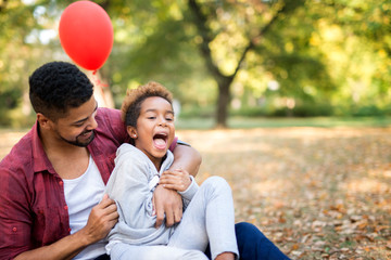Father tickling his daughter while she enjoys and laughs in his embrace. Family happiness all...