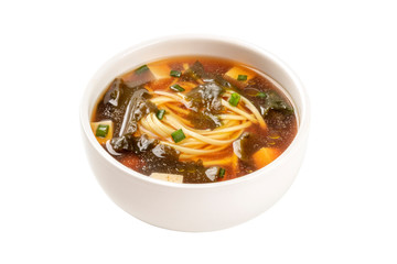 A photo of a bowl of miso soup with tofu, scallions, noodles, and wakame seaweed, isolated on a white background with a clipping path