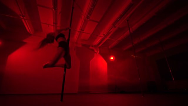 Adult sexy woman dancing dance in an intimate setting. Silhouette of a sexy woman dancing on red background. Pole dance from an old woman