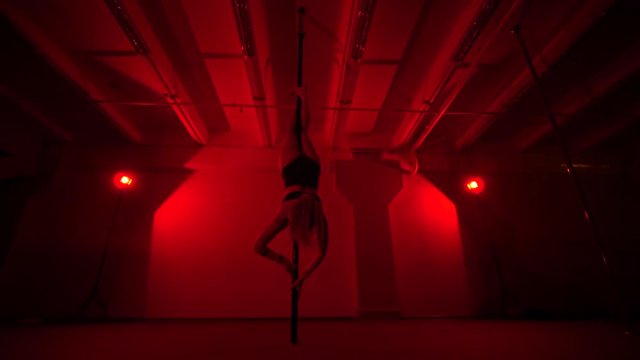 Adult sexy woman dancing dance in an intimate setting. Silhouette of a sexy woman dancing on red background. Pole dance from an old woman
