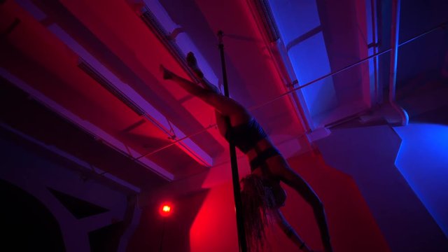 Adult sexy woman dancing dance in an intimate setting. Silhouette of a sexy woman dancing on red background. Pole dance from an old woman