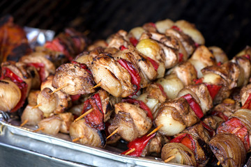 Close up of traditionally grilled pork and beef meat on a wooden stick. Eastern European traditional shish kebab with grilled vegetables.  