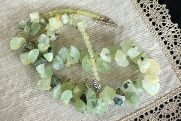 Beautiful green topaz stone necklace on natural linen napkin with crochet lace trim