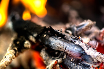 Ignite the fire. Warming up the cold winter nights. A macro shot of firewood, white dust and hot, glowing coal. Burning branches and wood. Flames in the fireplace, cozy home, warmth, love, romantic  