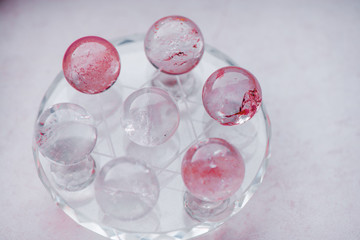 Macro shot of transparent crystal balls with colorful ornaments and sun reflections in it, on turquoise glass pad. Fortune telling. Love, money, luck, success.