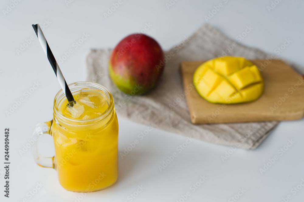 Wall mural Mango juice in a glass mason jar and mango on a wooden board, white background, side view - Wall murals