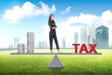 Young asian business woman standing balancing between income and tax