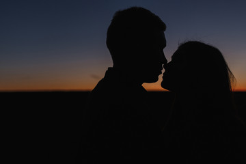 The silhouettes of the young man and woman in the sunset.