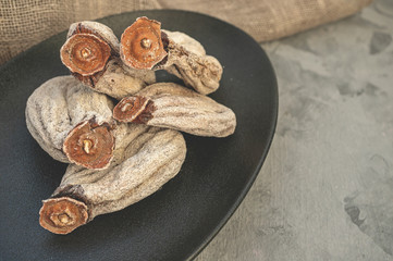 Dried persimmon on a black plate close-up. Copy space
