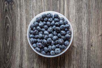 Ripe tasty blueberries and berries on a wooden table in a bowl